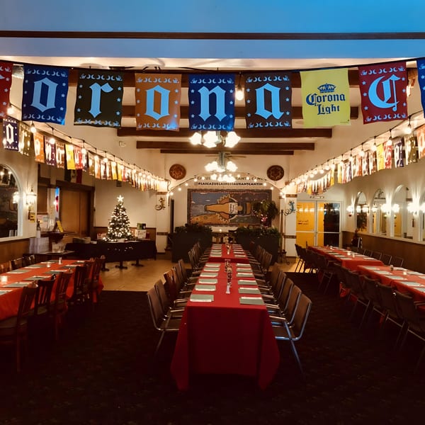Las Cazuelas Restaurant & Cantina dining room with long tables set for a party, decorated for Christmas.